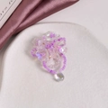 Detail von lila Perlenblumen-Schmuck mit einem farbenfrohen, schimmernden Kristallanhänger - Lila Blume
