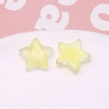 Macro shot of two yellow star-shaped glitter resin accessories in a white ceramic dish - 1 Piece / Yellow