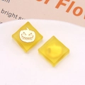 Vista macro di ciondoli quadrati in resina gialla traslucida con dettagli di zucca dorata - Giallo