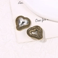 Dettaglio macro di ciondolo a cuore vintage con strass e motivi a spirale ornati - Cuore Zirconia Bianca