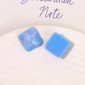 Macro shot of square sky blue resin charms with a marble texture and subtle glitter finish - Blue