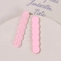 Nahaufnahme von glitzernden und rosa gewellten Harz-Haarspangen-Anhängern auf einem Keramiktablett - Rosa