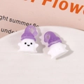Detailed macro shot of white resin ghost charms with purple hats for Halloween DIY - Purple