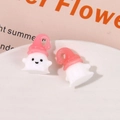 Macro shot of cute ghost resin charms with pink hats on a white ceramic plate - Pink