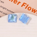 Macro shot of square blue resin charm with glitter and cat-eye shimmering effect - Blue