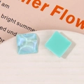 Macro shot of square resin charms with blue glitter wave and mint green finish - Green
