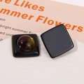 Detail view of retro geometric resin square charms in black and amber colors on a white stand - Black