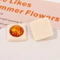 Macro detail of geometric square resin earrings with amber inserts on stone display - Milky White
