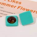 Macro view of geometric mint green square resin earrings with dark brown circular inlay details - Lake Green