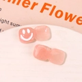 Macro detail of square pink resin charms with white smiley face for DIY jewelry - Pink