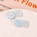 Macro shot of light blue resin square charm with a white smiley face for jewelry DIY - Blue
