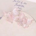 Detailed macro view of pearlescent pink acrylic butterfly jewelry accessories in soft light - Pink