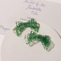 Detail of green lace-embedded acrylic bow hair clips on a decorative white tray - Green