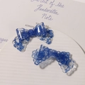 Close-up of elegant blue lace pattern bow hair clips on a white ceramic display tray - Blue