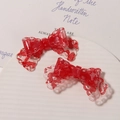Pair of red bow-shaped hair clips with floral lace texture on a ceramic tray - Red