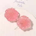 Dettaglio di orecchini a rosa in resina rosa con petali traslucidi su piatto bianco - Rosa