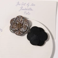 Détail d'une broche fleur en strass colorés et dos en feutre noir sur un plateau - Argenté