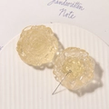 Close-up of translucent light yellow resin daisy earrings on a white ceramic plate - Beige