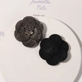 Gros plan détaillé d'accessoires camélia étincelants en strass sur une assiette en céramique - Gris
