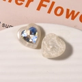 Vista macro di ciondoli a cuore in resina con strass sfaccettati su vassoio ceramico - Bianco