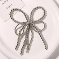 Dettaglio di un fiocco di perline d'argento con nappe su un piatto di ceramica bianco - Stile Argento Galvanico