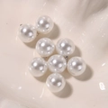 Macro shot of white round lustrous pearls with silver metal loops for DIY jewelry making - 16mm