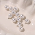 Macro shot of white round pearl charms with silver ring connectors for DIY jewelry making - 12mm