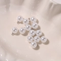 Macro shot of glossy white round pearl pendants with silver loops in a shell dish - 10mm