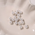 Macro shot of round white pearl pendants with silver loops in a white shell dish - 8mm