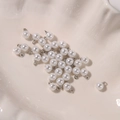 Macro detail of high-luster white pearl pendants with silver metal bails for DIY jewelry - 6mm