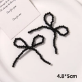 Detailansicht eines handgefertigten schwarzen Perlenbogens auf einer weißen Keramikplatte - Stil 8 (4.8*5cm) / Schwarz Klein