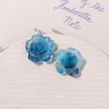 Dettaglio macro di due ciondoli a forma di rosa in resina blu trasparente con glitter interni - Blu