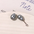 Makroaufnahme silberfarbener Tropfenperlen für DIY-Schmuck auf weißer Keramik - Klein Grau