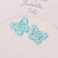 Detailed macro view of mint green and pearl blue acrylic butterfly shoe charms with glitter - Blue