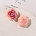 Macro detail of resin rose and camellia charms with matte and glossy textures for DIY - Pink