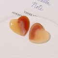 Close-up of heart-shaped resin charms with orange marble texture on a white tray - Orange Agate Texture
