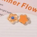 Close-up of translucent orange glitter resin flower charms on a wavy white tray - Turmeric