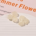 Makro-Detail von cremeweißen Acryl-Blütenanhängern für DIY-Schmuck auf einem Keramikteller - 1 Stück / Cremeweiß