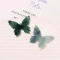 Detailed close-up of butterfly-shaped resin charms with artistic ink marble patterns - Green