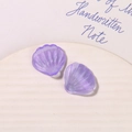 Macro shot of purple translucent shell-shaped acrylic charms with fine glitters for DIY crafts - Purple