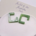 Dettaglio di orecchini a C in resina con trama marmo verde su vassoio in ceramica - Verde