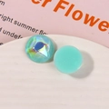 Macro shot of circular resin charms featuring aurora polar and light cyan glitter finishes - Green