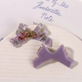 Detail of purple resin bows with embedded dried flowers on a white ceramic plate - Purple