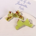 Detail of resin bow hair clips with embedded dried flowers and pearls on ceramic tray - Green