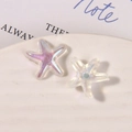 Macro shot of iridescent resin starfish charms with glitter finish on a white ceramic tray - Starfish