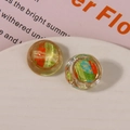 Macro shot of circular resin charm with colorful swirl patterns and gold metal edge - Green