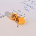 Detail of yellow cube resin beads with golden steampunk gear charm on a white tray - Yellow