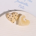 Dettaglio macro di accessori in resina a forma di cuore con marmo e pois neri - Beige