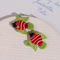 Détail macro de perles en verre poisson tropical peintes à la main avec rayures rouges - Style Rouge-Vert