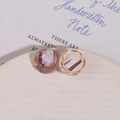 Macro detail of round resin earring charms with gold metal edges and marble texture - Purple